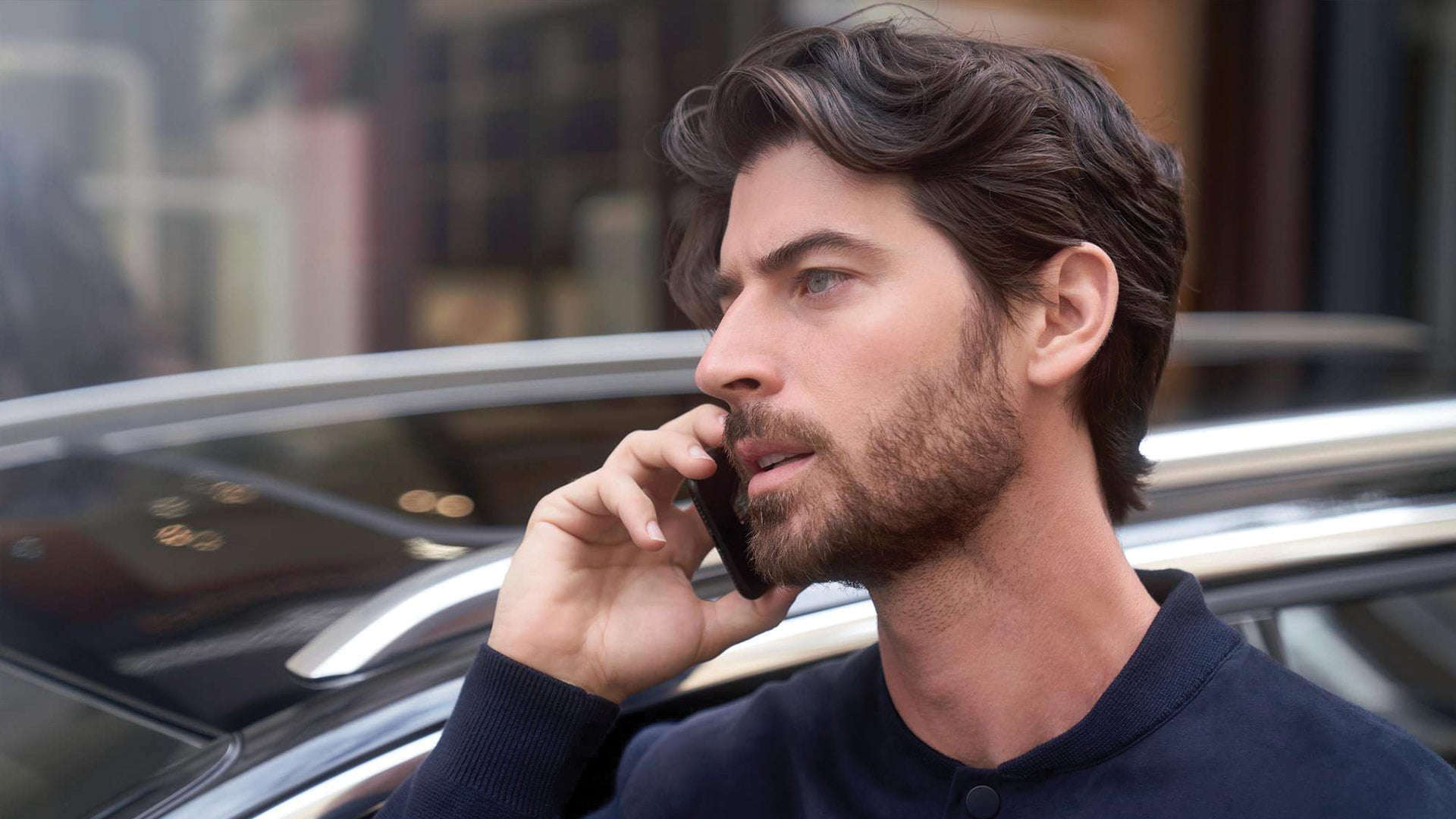 Чоловік тримає телефон біля вуха, стоячи перед автомобілем Peugeot