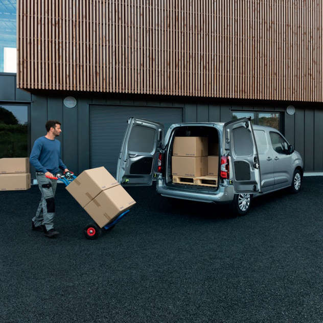 Чоловік з вантажним візком біля Peugeot Partner